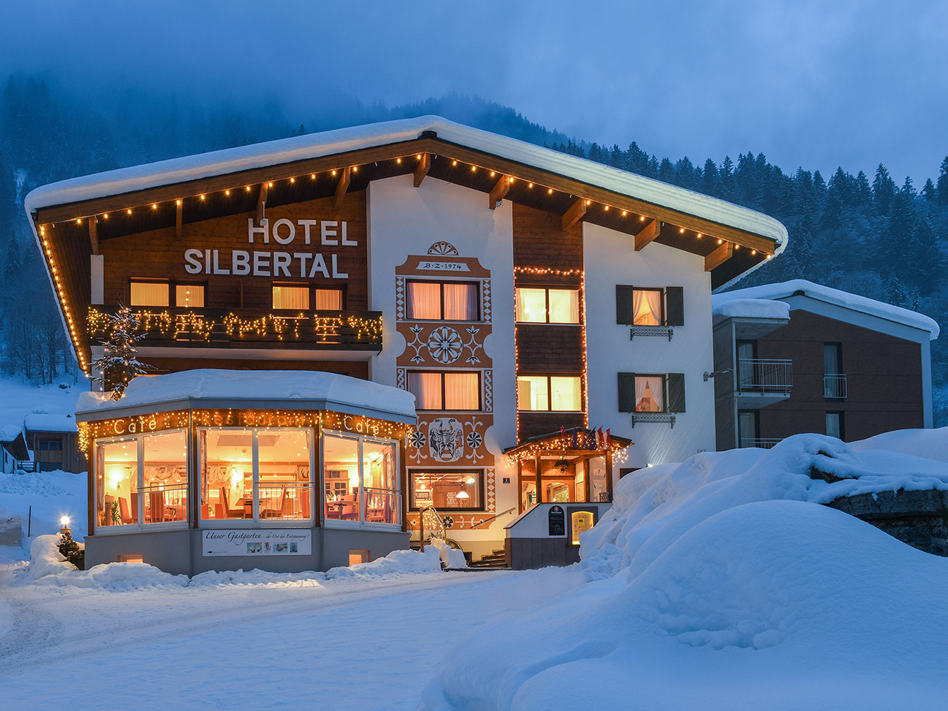 Hotel Silbertal im Winter mit verschneiter Landschaft und stimmungsvoller Weihnachtsbeleuchtung im Montafon