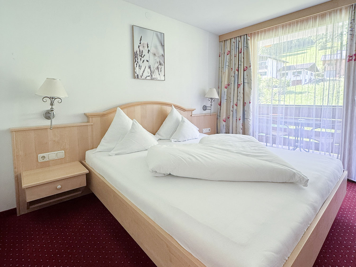 Doppelbett im Doppelzimmer mit Balkon des Hotel Silbertal im Montafon