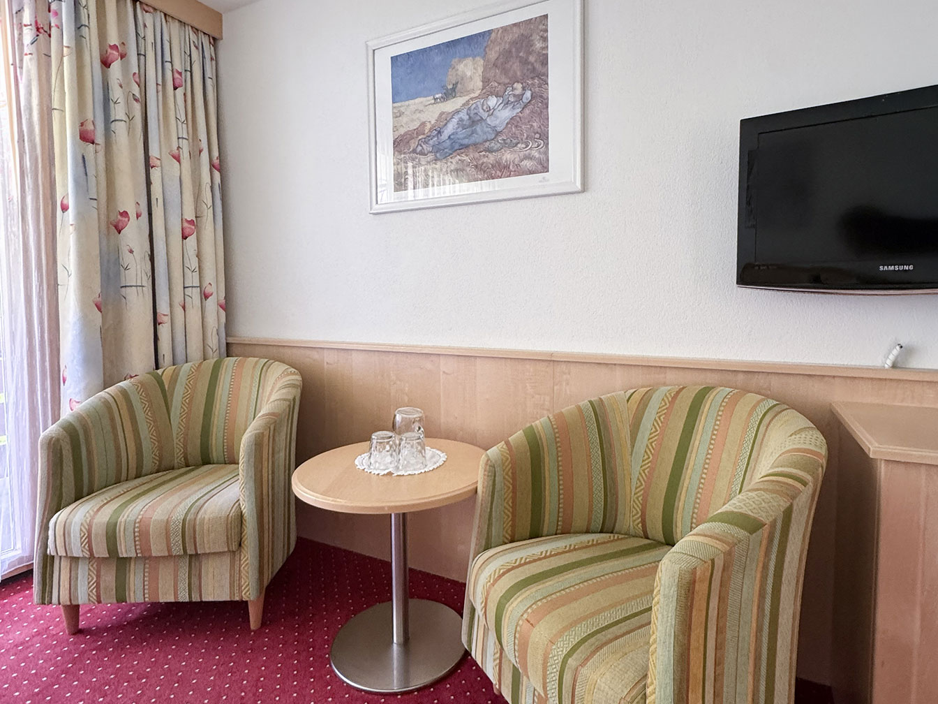 Sitzbereich mit Sessel, Tisch und TV im Doppelzimmer mit Balkon des Hotel Silbertal