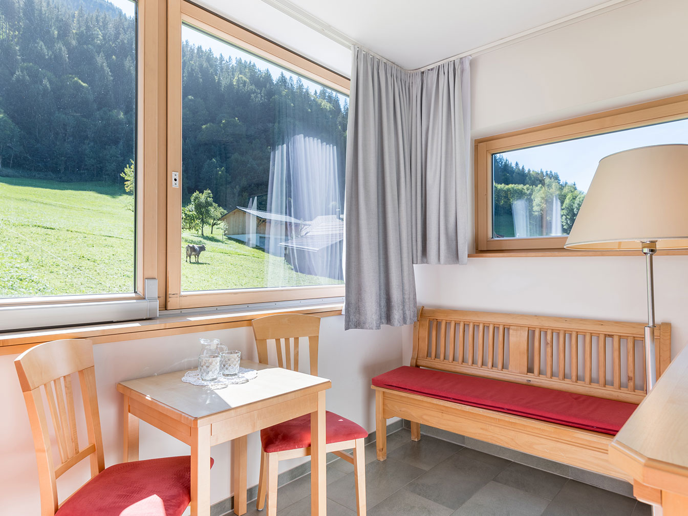 Sitzbank am Panoramafenster im Doppelzimmer Silbertal mit Blick auf die Bergwelt
