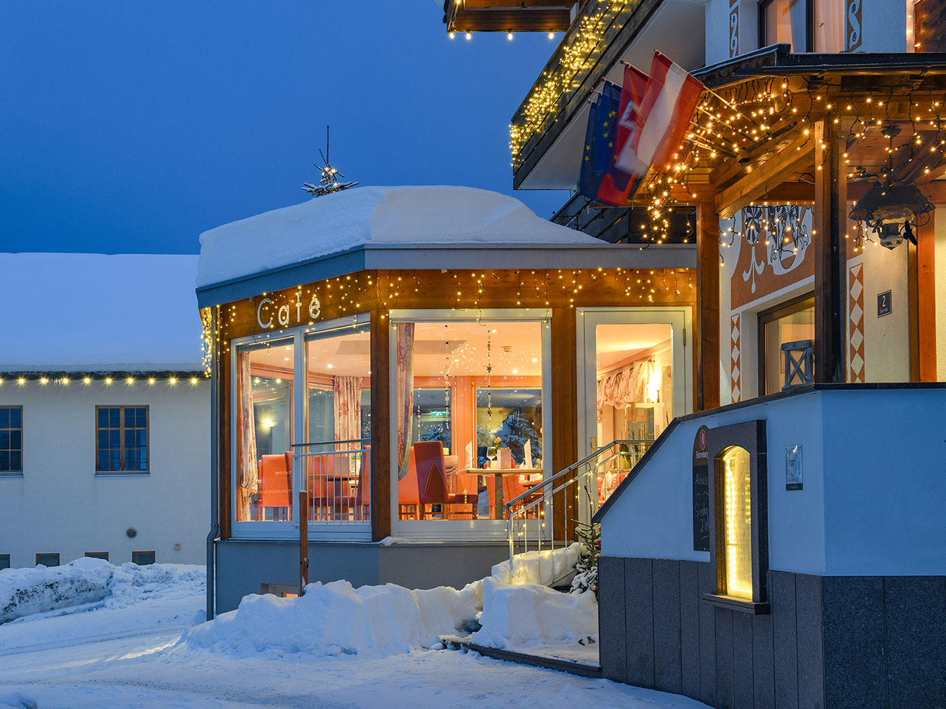 Hotel Silbertal am Winterabend mit verschneiter Terrasse und stimmungsvoller Weihnachtsbeleuchtung